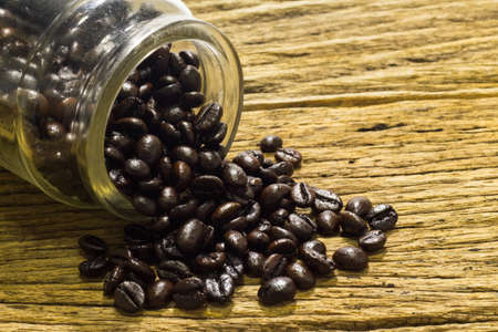 Glass of coffee beans wooden background