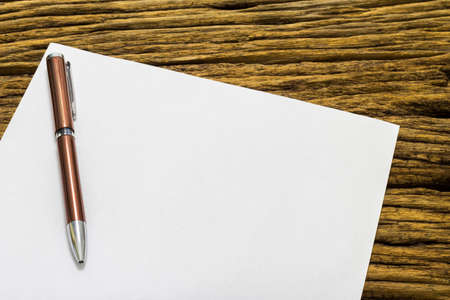 Blank sheet of paper and pen on old wooden background.の写真素材