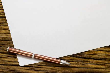 Blank sheet of paper and pen on old wooden background.