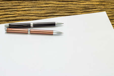 Blank sheet of paper and pens on old wooden background.の写真素材