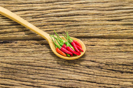 Red peppers in wooden spoon on wooden background.の写真素材