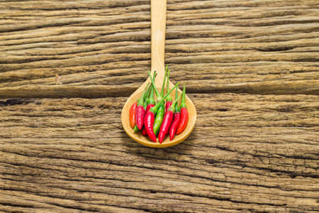 Red peppers in wooden spoon on wooden background.の写真素材