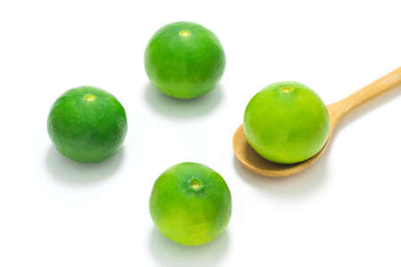Green lime in wooden spoon isolated on white background.の写真素材