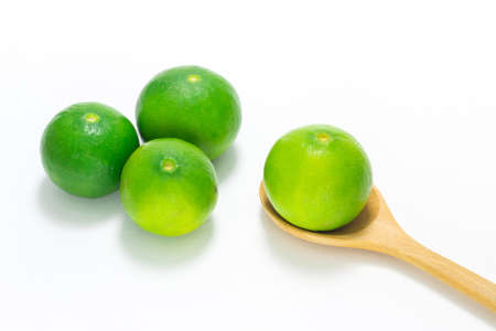 Green lime in wooden spoon isolated on white background.の写真素材