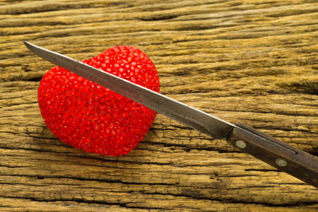 Knife cut half of red heart wooden background.の写真素材