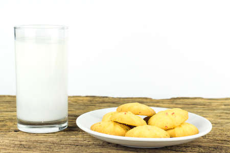 Cookies in dish with a glass of cold milk on wooden table and white background.の写真素材