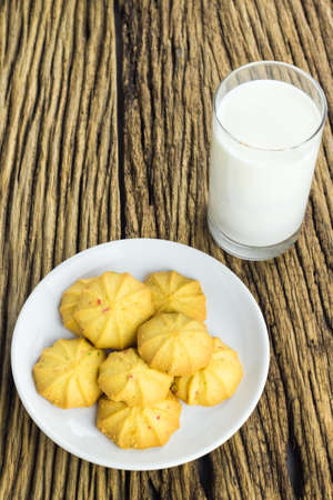 Cookies in dish with a glass of cold milk on wooden background.の写真素材