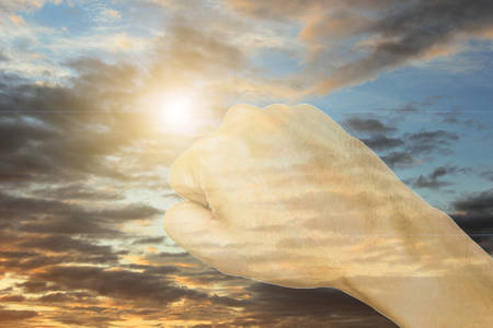 Double exposure of hand fist, with the sky background.の写真素材