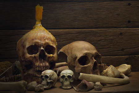 Still Life of skull and bone with fetters and candle on the wooden plank in dim light night / Select focus.の写真素材