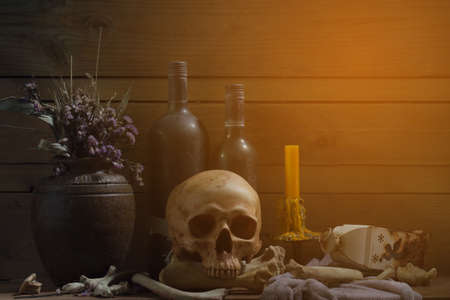 Still Life of skull and bone with fetters and candle on the wooden plank in dim light night / Select focus.の写真素材