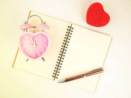 Top view of notebook alarm clock and pen with red heart, Vintage filter.の写真素材