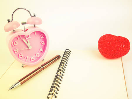 Notebook alarm clock and pen with red heart, Vintage filter.の写真素材