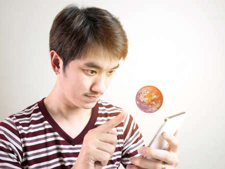Young Asian man using smartphone with earth on gray background,の写真素材