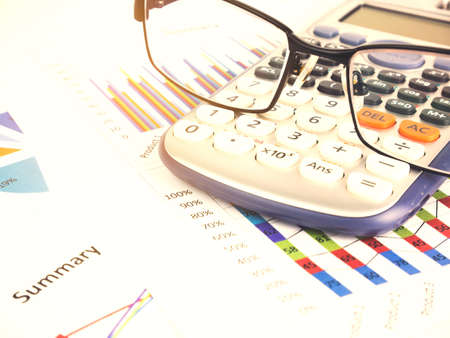 Business chart near calculator by unfocused glasses, Financial concept.の写真素材