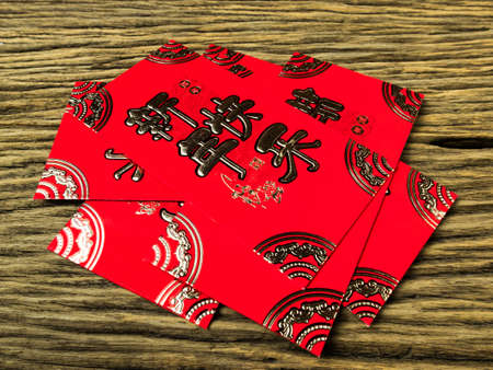 Red envelope on wooden background with February for gift Chinese New Year. Chinese text on envelope meaning Happy Chinese New Year.の写真素材