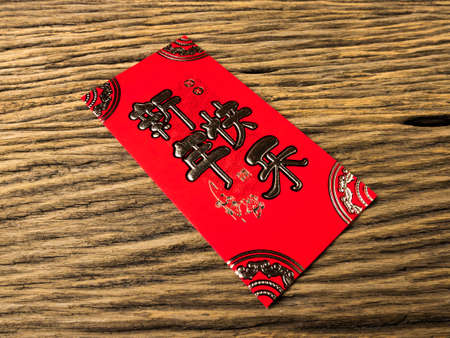 Red envelope on wooden background with February for gift Chinese New Year. Chinese text on envelope meaning Happy Chinese New Year.の写真素材