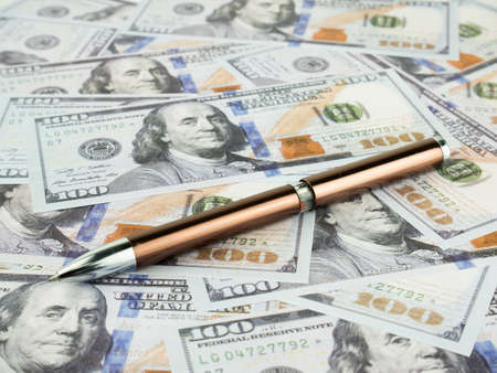 It is a lot of One hundred dollars banknotes pile and pen as background.