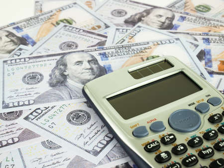 It is a lot of One hundred dollars banknotes pile and Calculator as background.の写真素材