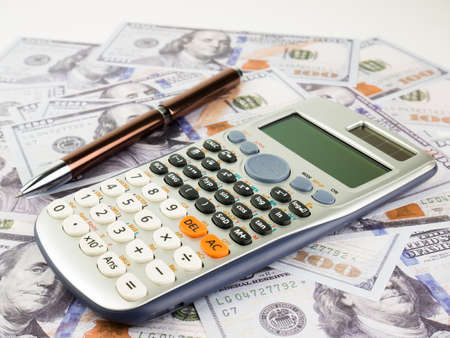 It is a lot of One hundred dollars banknotes pile with calculator and pen as background.の写真素材