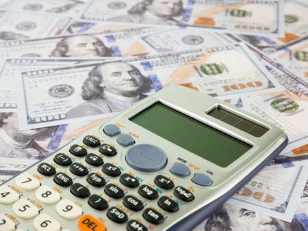 It is a lot of One hundred dollars banknotes pile and Calculator as background.の写真素材