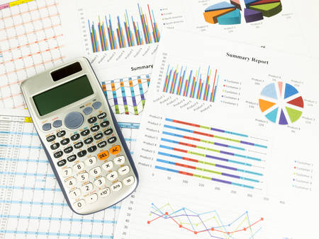 Calculator with business graphs and report information background for financial and economy concepts.の写真素材