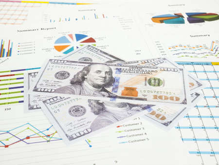 Dollar banknotes with business graphs and report information background for financial and economy concepts.の写真素材