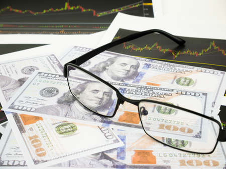 Glasses with business graphs and report information background for financial and economy concepts.の写真素材