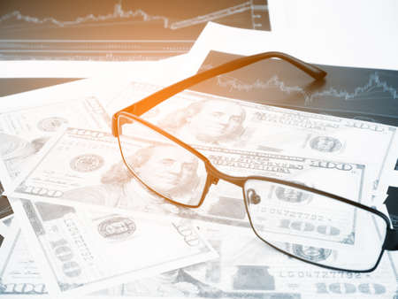 Glasses with business graphs and report information background for financial and economy concepts, Blue tone.の写真素材