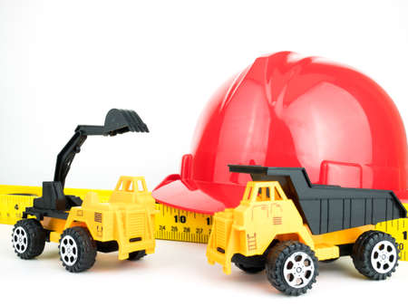 Red safety helmet with Mechanical digger and Truck toy, Engineering construction concept.の写真素材