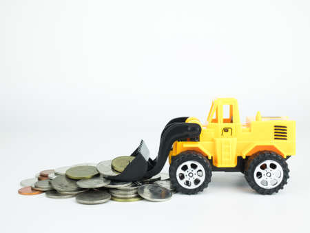 Toy Bulldozers with coins on white background, Business concept.の写真素材