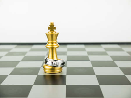 Diamond ring with king chess piece on the board, Wedding Concept.の写真素材