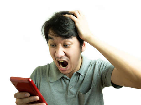 Young asian man yelling with phone on white background.の写真素材