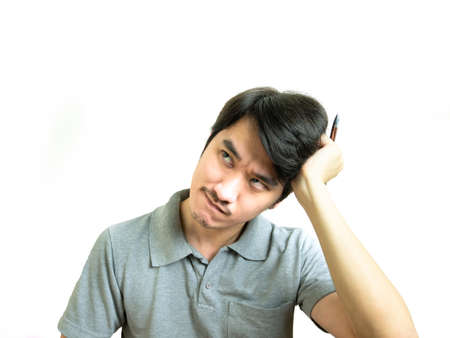 Young Asian man thinking with pen on white background.の写真素材