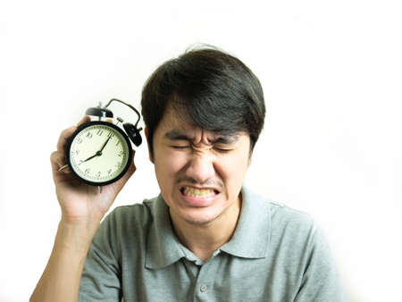 Asian young man with alarm clock in hand at 7 o'clock in the morning.の写真素材