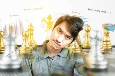 Young Asian man thinking with Chess board versus Finance graph chart, Financial strategy concept, Business concept.の写真素材