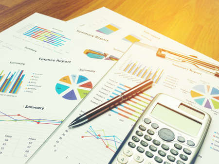 Business report chart and Financial graph analysis with pen and calculator on table.の写真素材