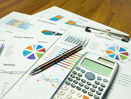 Business report chart and Financial graph analysis with pen and calculator on table.の写真素材