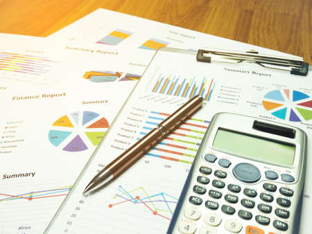 Business report chart and Financial graph analysis with pen and calculator on table.の写真素材