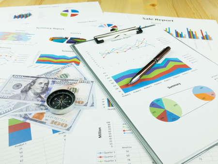 Business report chart and Financial graph analysis with dollar money, pen and compass on table.の写真素材