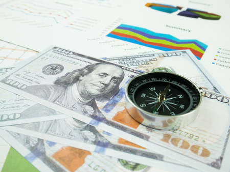 Business report chart and Financial graph analysis with dollar money and compass on table.の写真素材