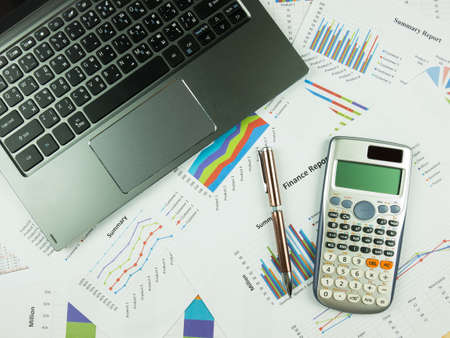 Business report chart and Financial graph analysis with notebook, calculator and pen on table.の写真素材