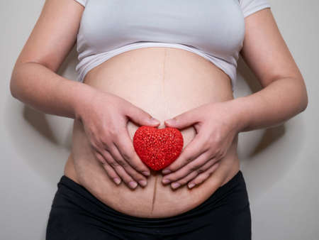 Close Up Of Pregnant Woman Holding red heart.の写真素材