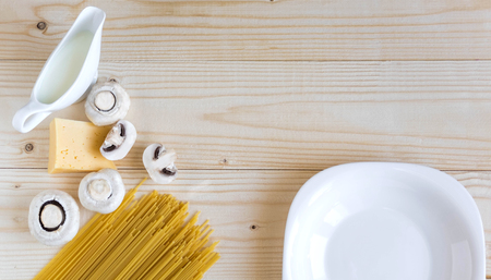 Wooden background with cheese, spaghetti and mushrooms. cream. Background for restaurants and cafes. Wooden background with pasta.の写真素材