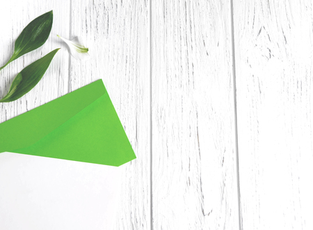 Mock up blank paper and envelope on white wooden background with natural flowers of white color. Blank, frame for text.の写真素材