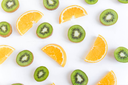 Tropical pattern on a white background. Slices of kiwi and orange on a white wooden background.の写真素材