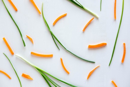 Pattern with green onions and carrot slices on a white wooden background. Kitchen Pattern.の写真素材
