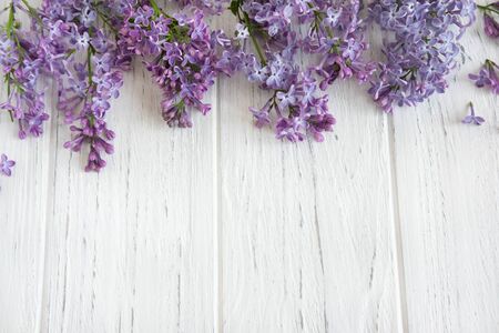 Frame for a banner of lilac flowers on a white wooden background. Background with spring flowers. Background with lilac flowersの写真素材