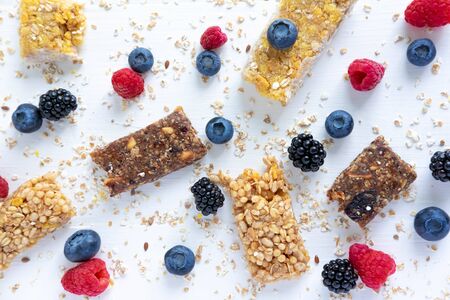 Pattern with cereal bars and blueberries, blackberries and raspberries with oatmeal. Healthy snacks