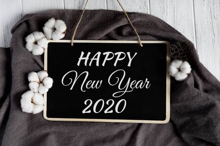 Happy New Year. Greeting Christmas card with cotton flowers on a whitewashed wooden background....