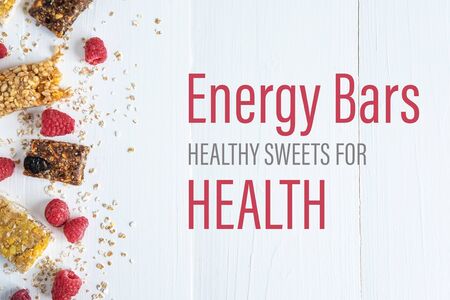 Energy bars healthy sweets for health. The inscription on a white wooden background with granola and fresh raspberries.の写真素材